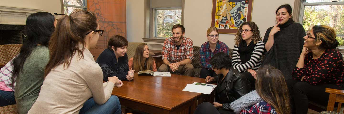 graduate students laughing and smiling in a living room setting